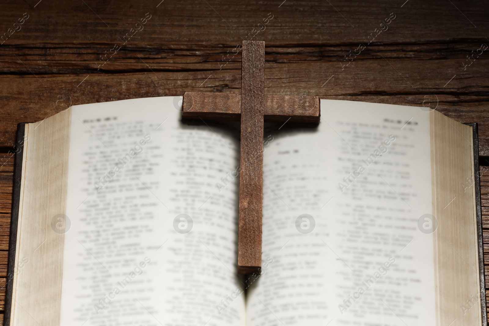 Photo of Bible and cross on wooden table, above view. Religion of Christianity