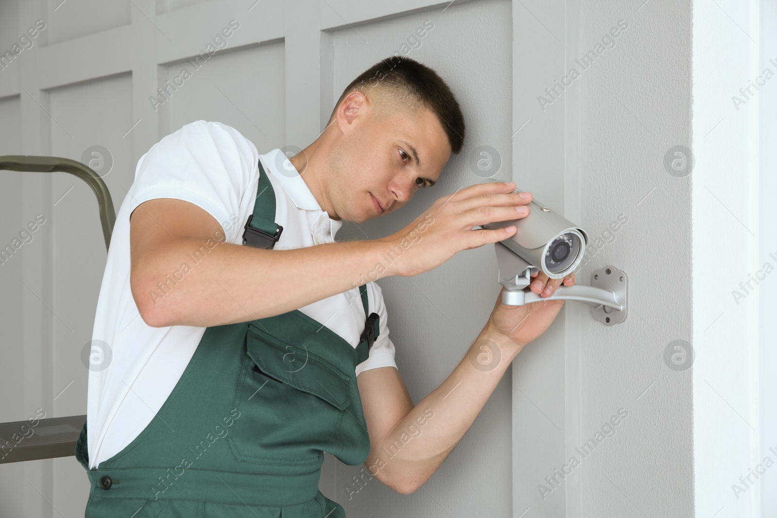 Photo of Technician installing CCTV camera on wall indoors