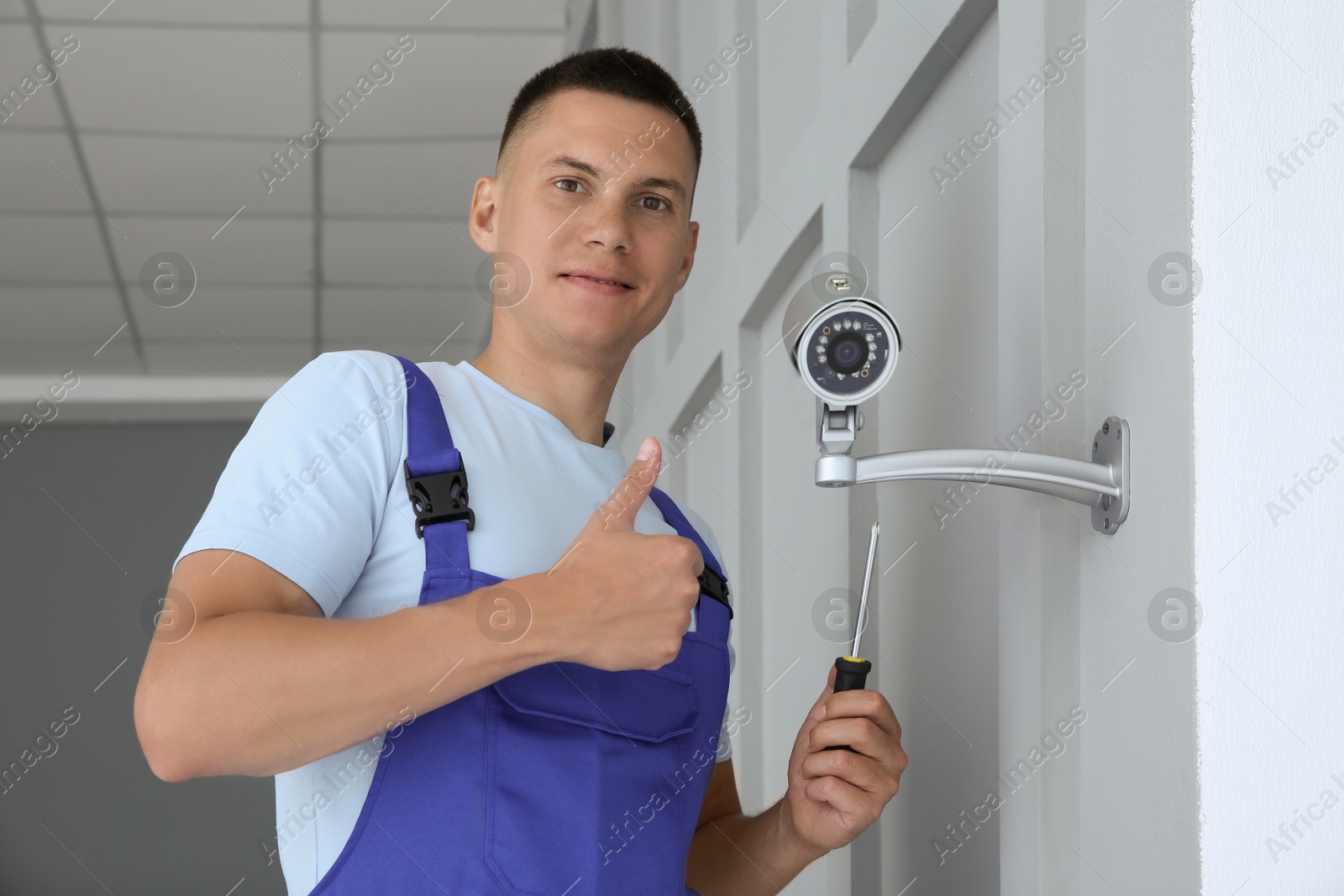 Photo of Technician with screwdriver showing thumb up near CCTV camera