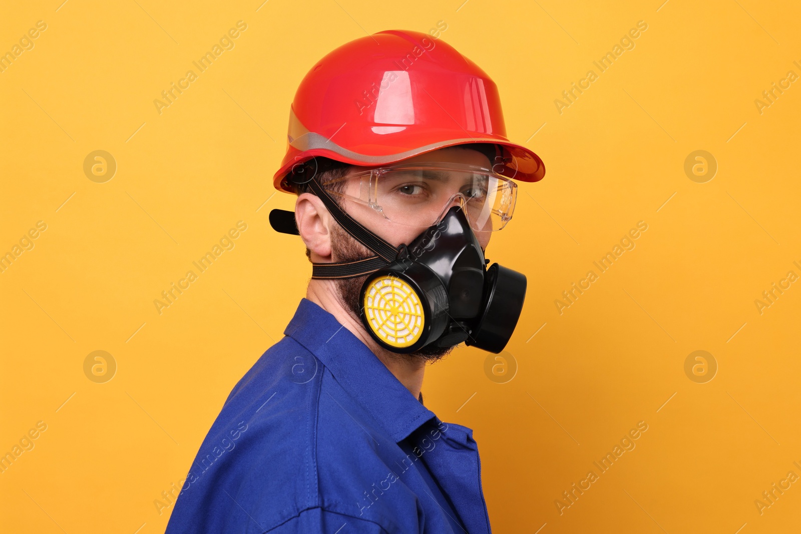 Photo of Man in respirator mask and hard hat on yellow background