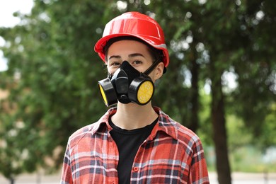 Photo of Woman in respirator mask and helmet outdoors. Protective equipment