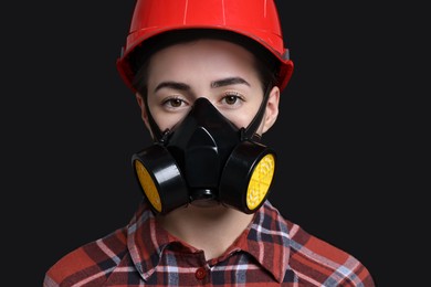 Woman in respirator and helmet on black background