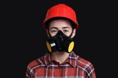 Woman in respirator and helmet on black background