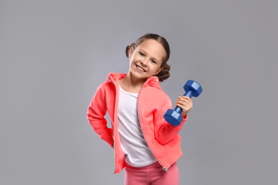 Cute little girl with dumbbell on grey background