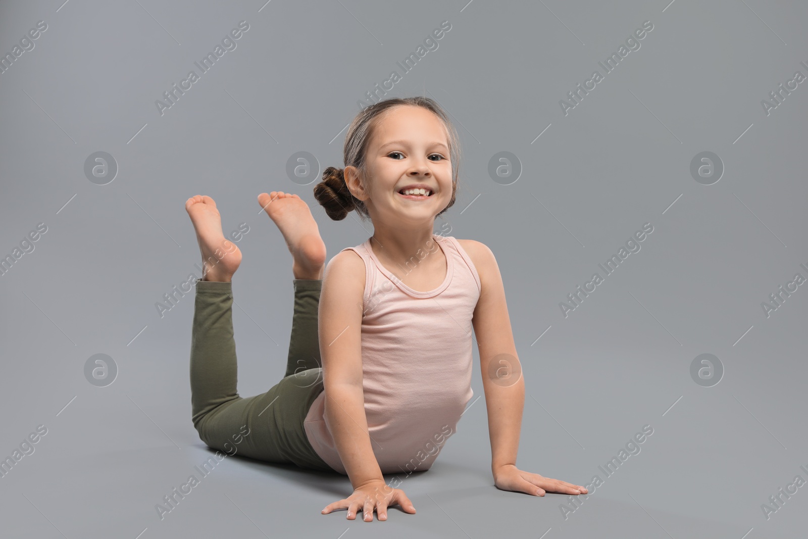 Photo of Cute little girl stretching on grey background