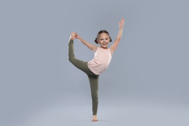 Photo of Cute little girl stretching on grey background