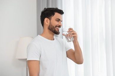 Happy man with glass of water at morning