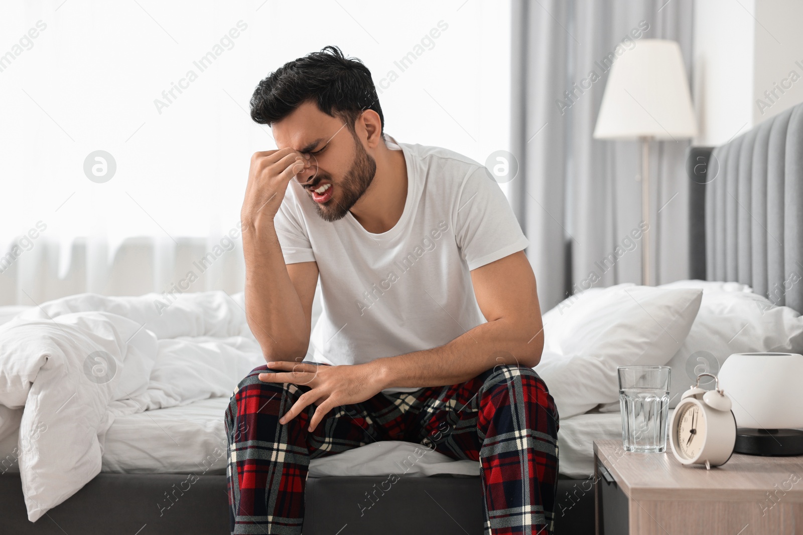 Photo of Man suffering from headache on bed at morning