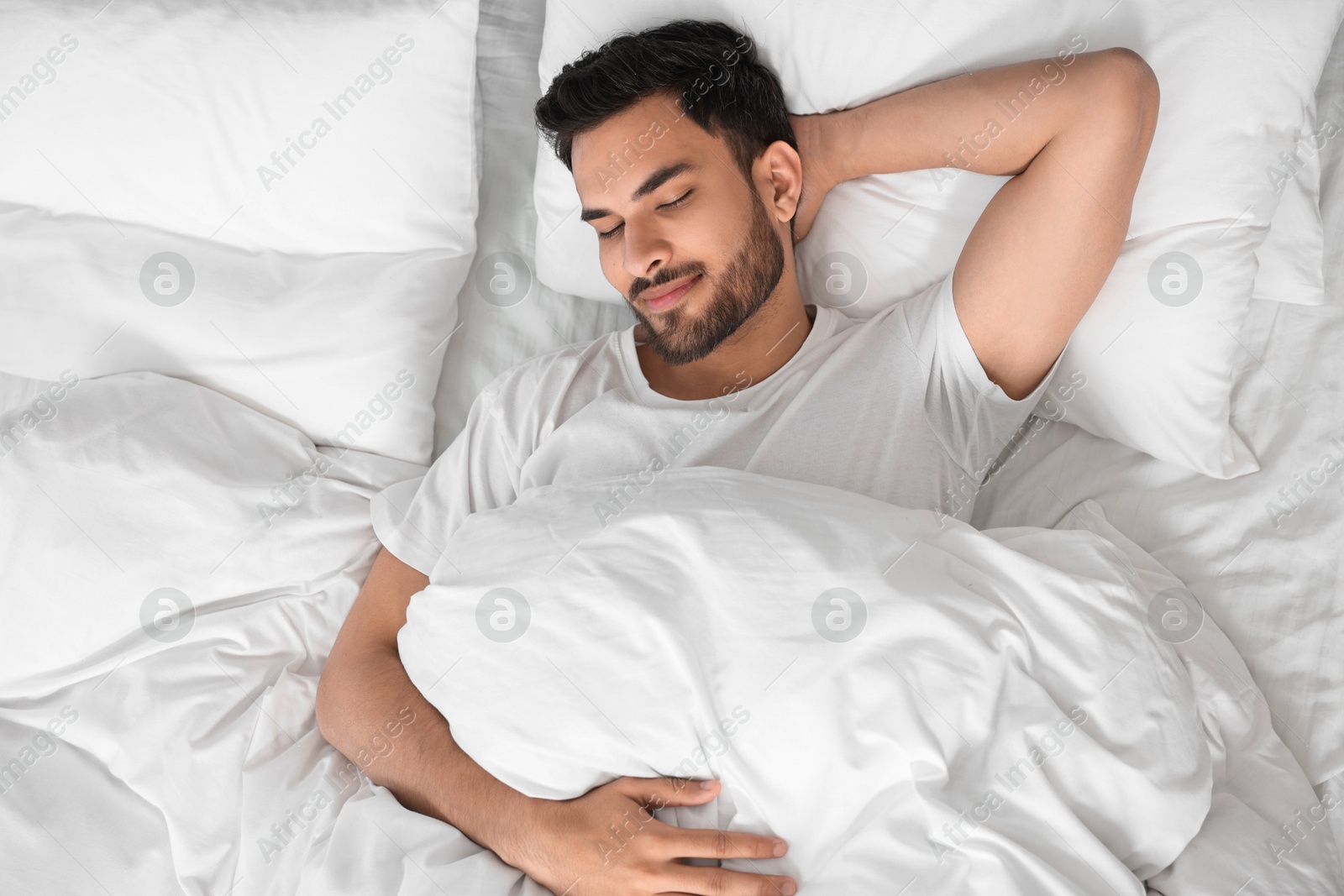 Photo of Handsome man sleeping in bed at morning, top view