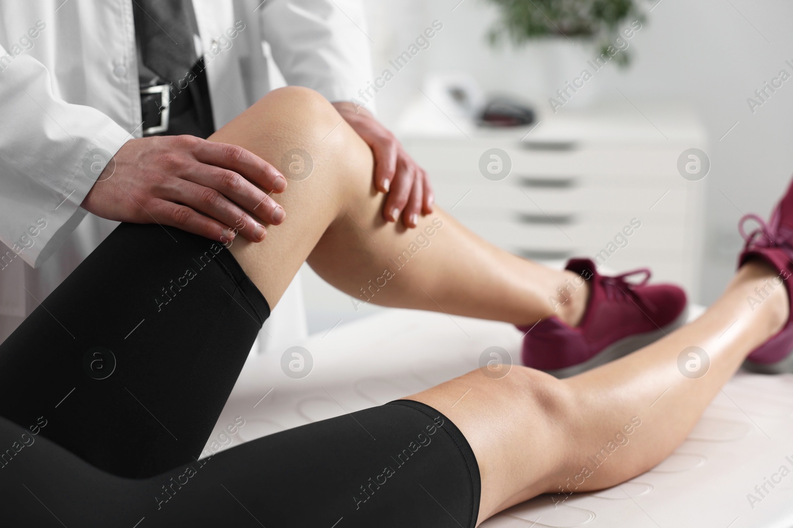 Photo of Sports injury. Doctor examining patient's leg in hospital, closeup