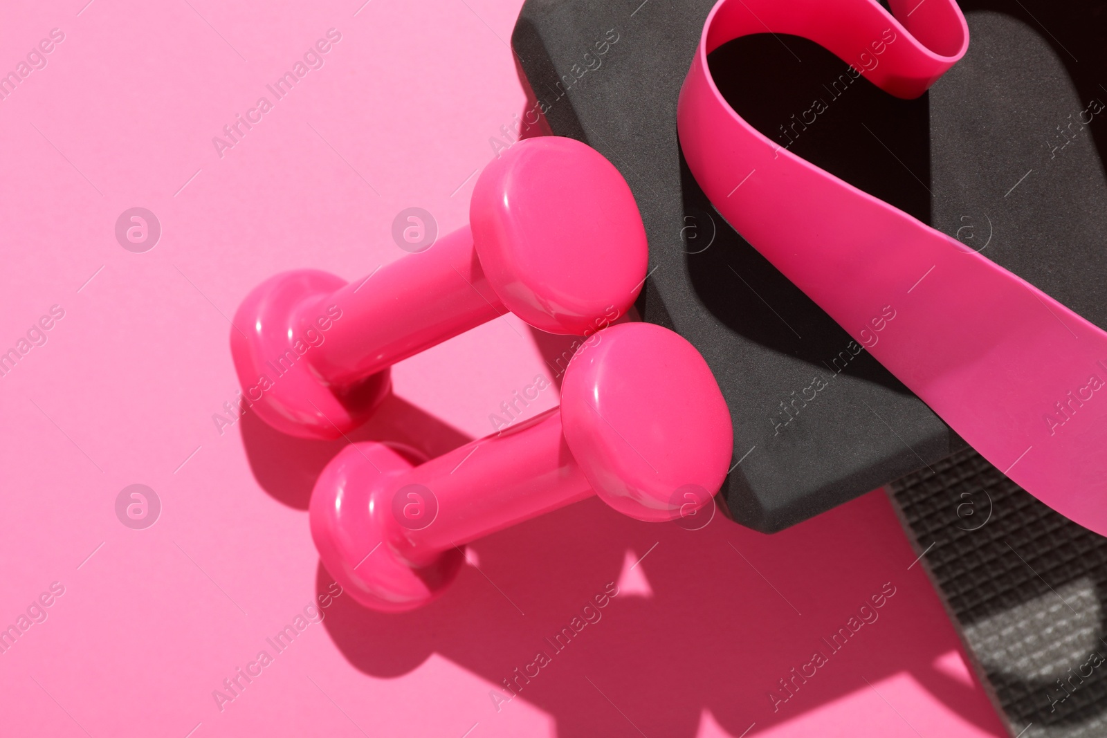 Photo of Dumbbells, fitness elastic band and yoga block on pink background, flat lay