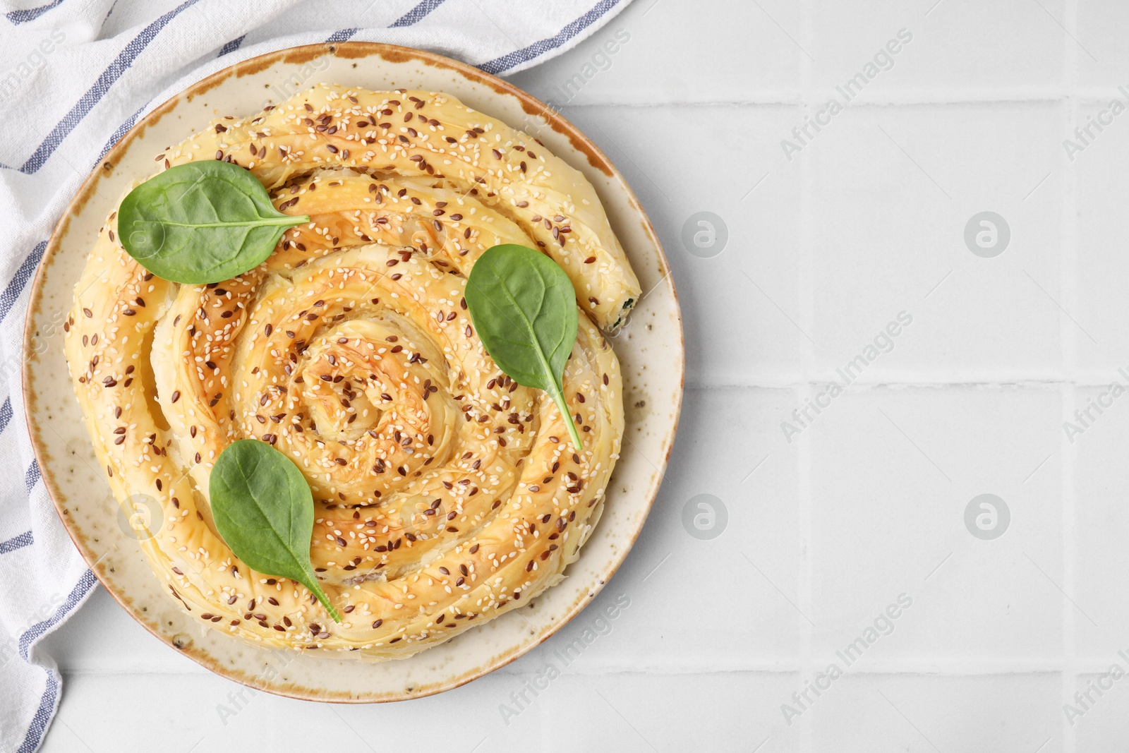 Photo of Delicious puff pastry with spinach on white tiled table, top view. Space for text