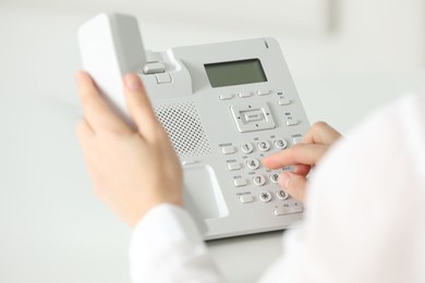 Photo of Assistant dialing number on telephone at table, closeup