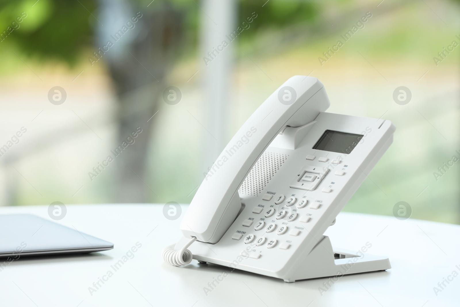 Photo of White telephone on table against blurred background