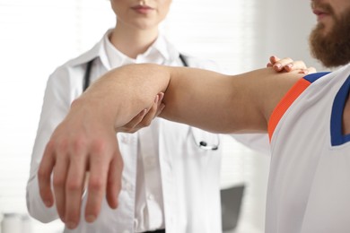 Photo of Sports injury. Doctor examining patient's hand in hospital, closeup