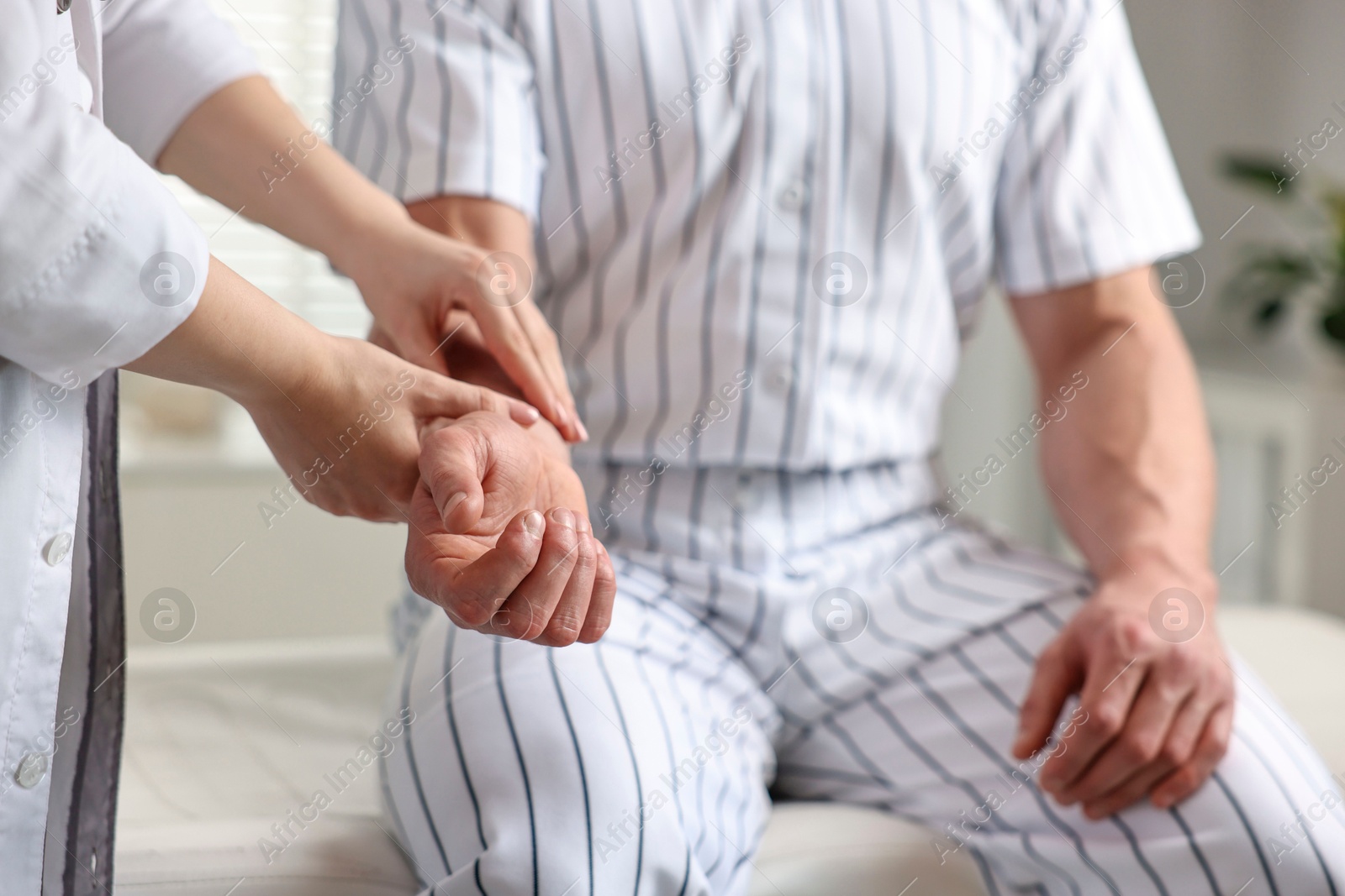 Photo of Sports injury. Doctor examining patient's hand in hospital, closeup