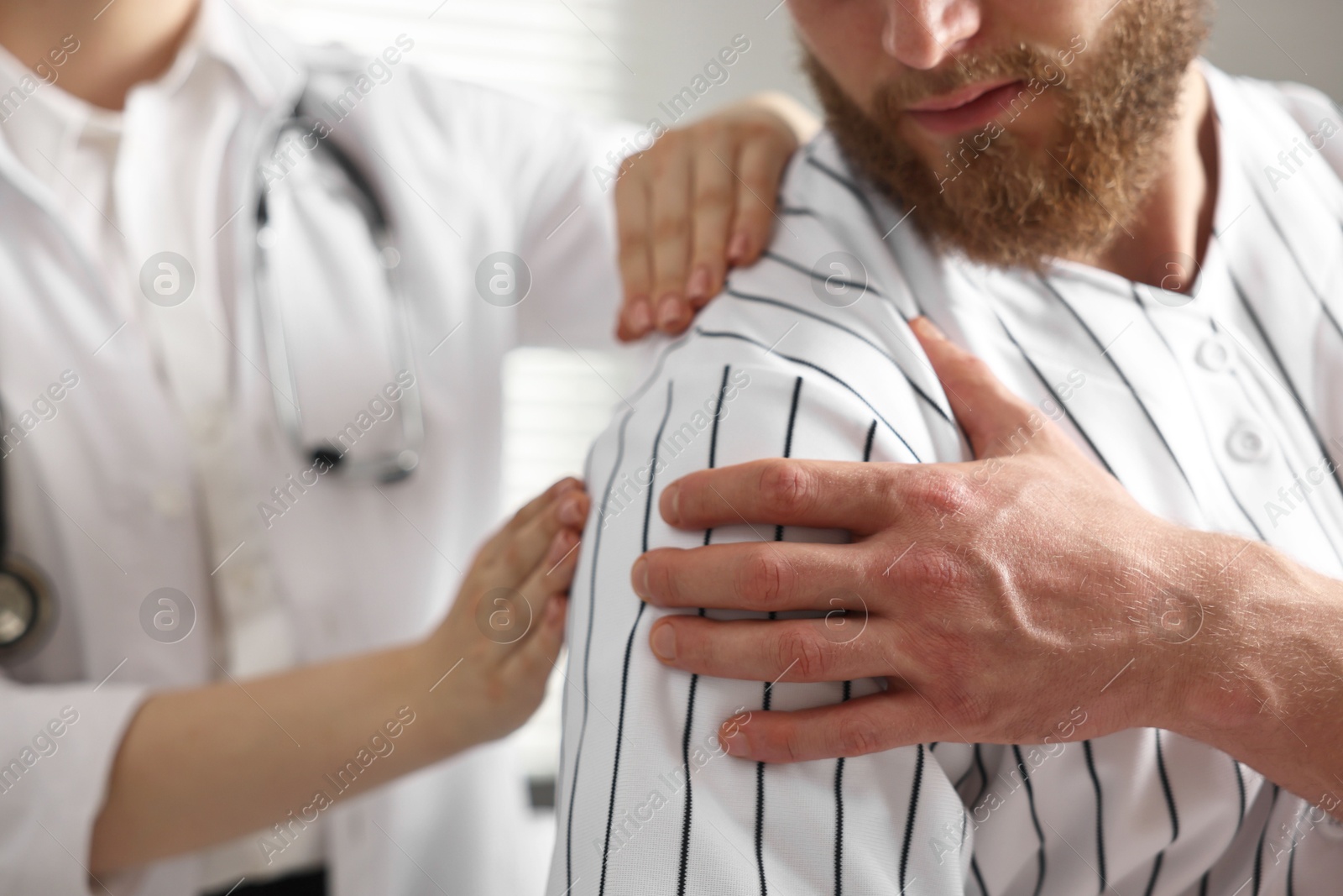 Photo of Sports injury. Doctor examining patient's shoulder in hospital, closeup