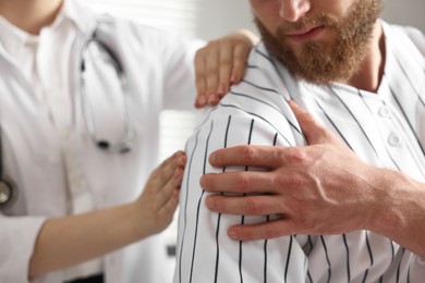 Photo of Sports injury. Doctor examining patient's shoulder in hospital, closeup