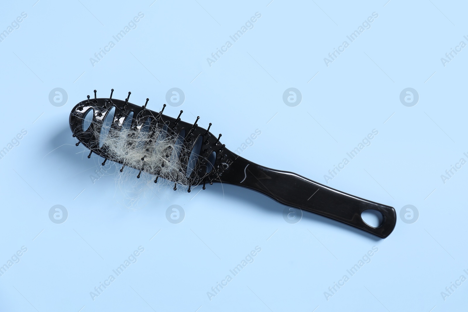 Photo of Brush with lost hair on light blue background