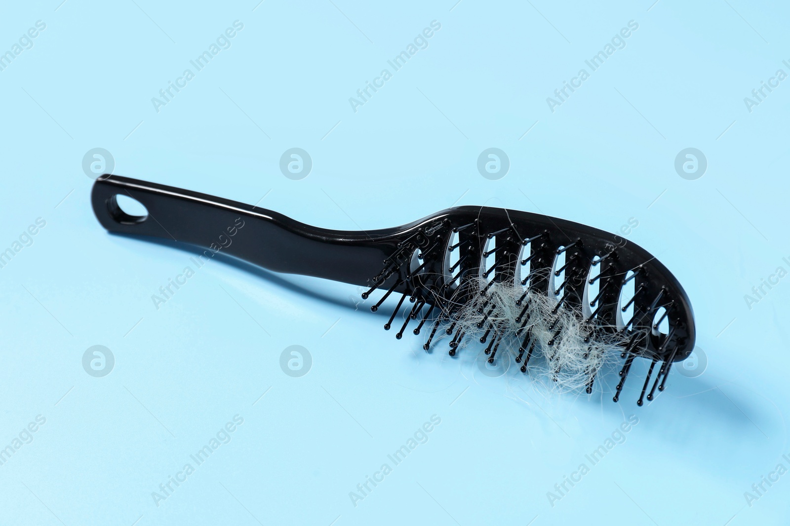 Photo of Brush with lost hair on light blue background