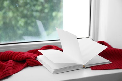 Red knitted scarf and notebook on windowsill