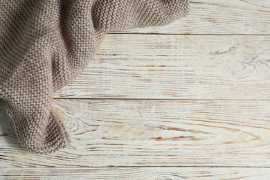 Photo of Gray knitted scarf on white wooden table, top view. Space for text