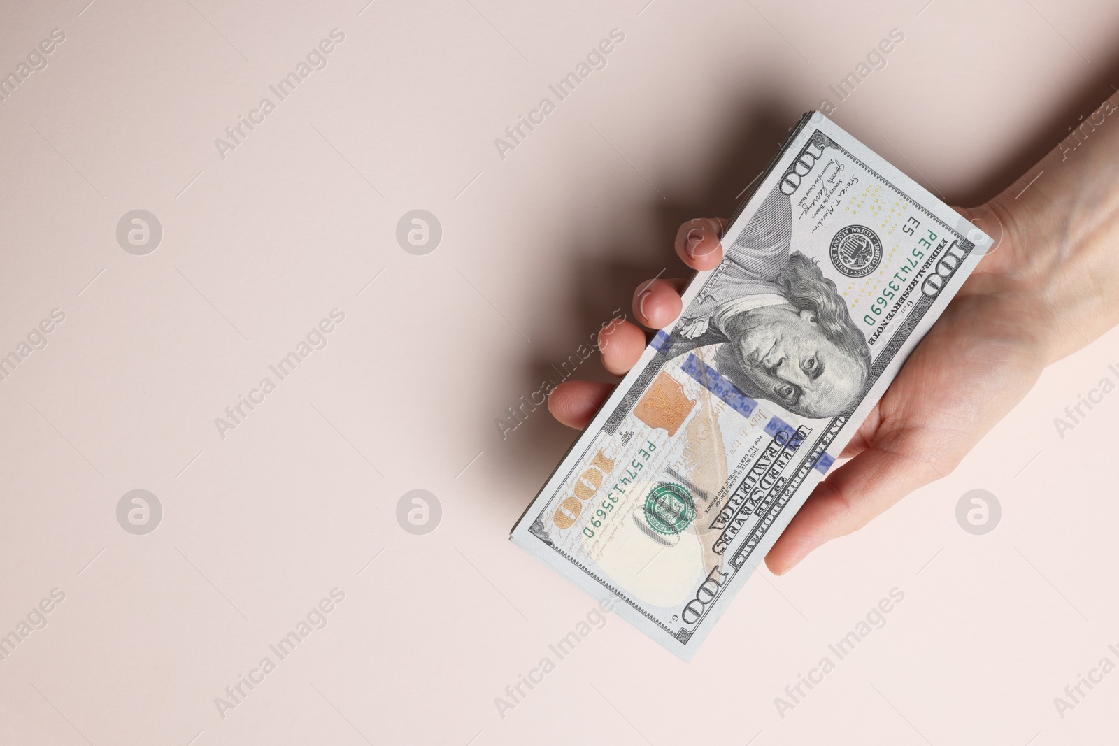 Photo of Money exchange. Woman holding dollar banknotes on beige background, top view. Space for text