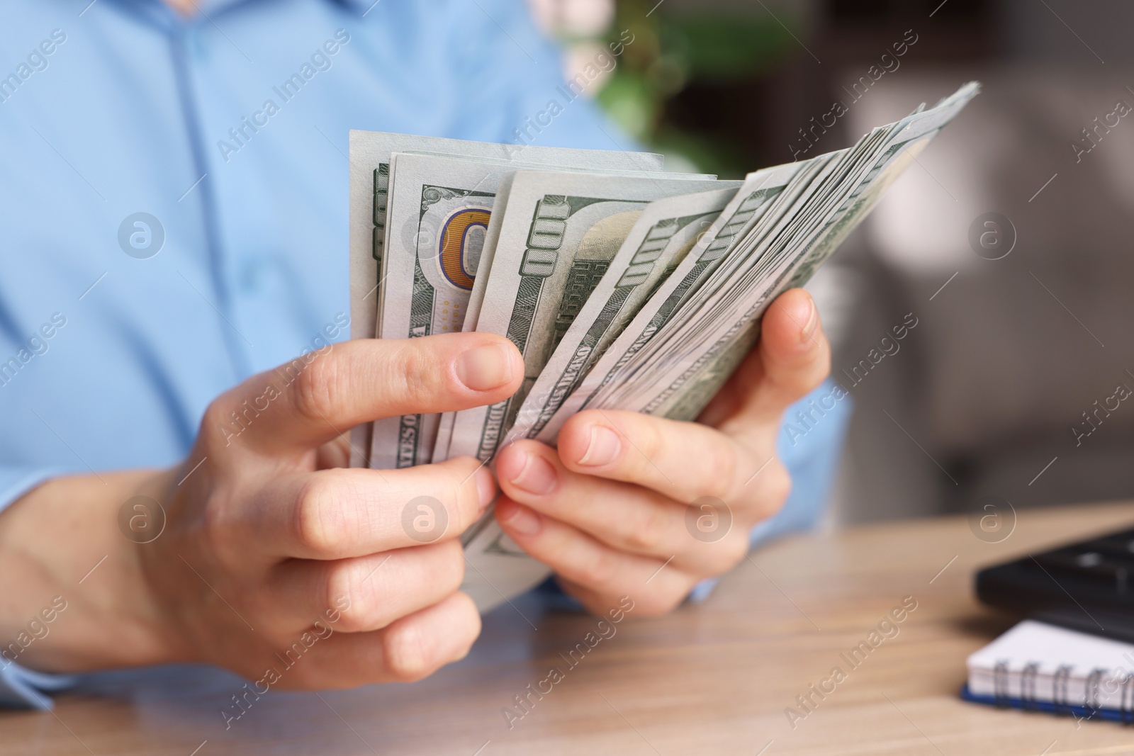 Photo of Money exchange. Woman counting dollar banknotes at wooden table, closeup