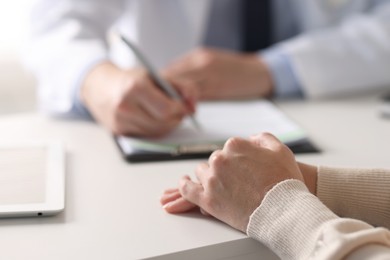 Professional doctor working with patient at white table in hospital, closeup