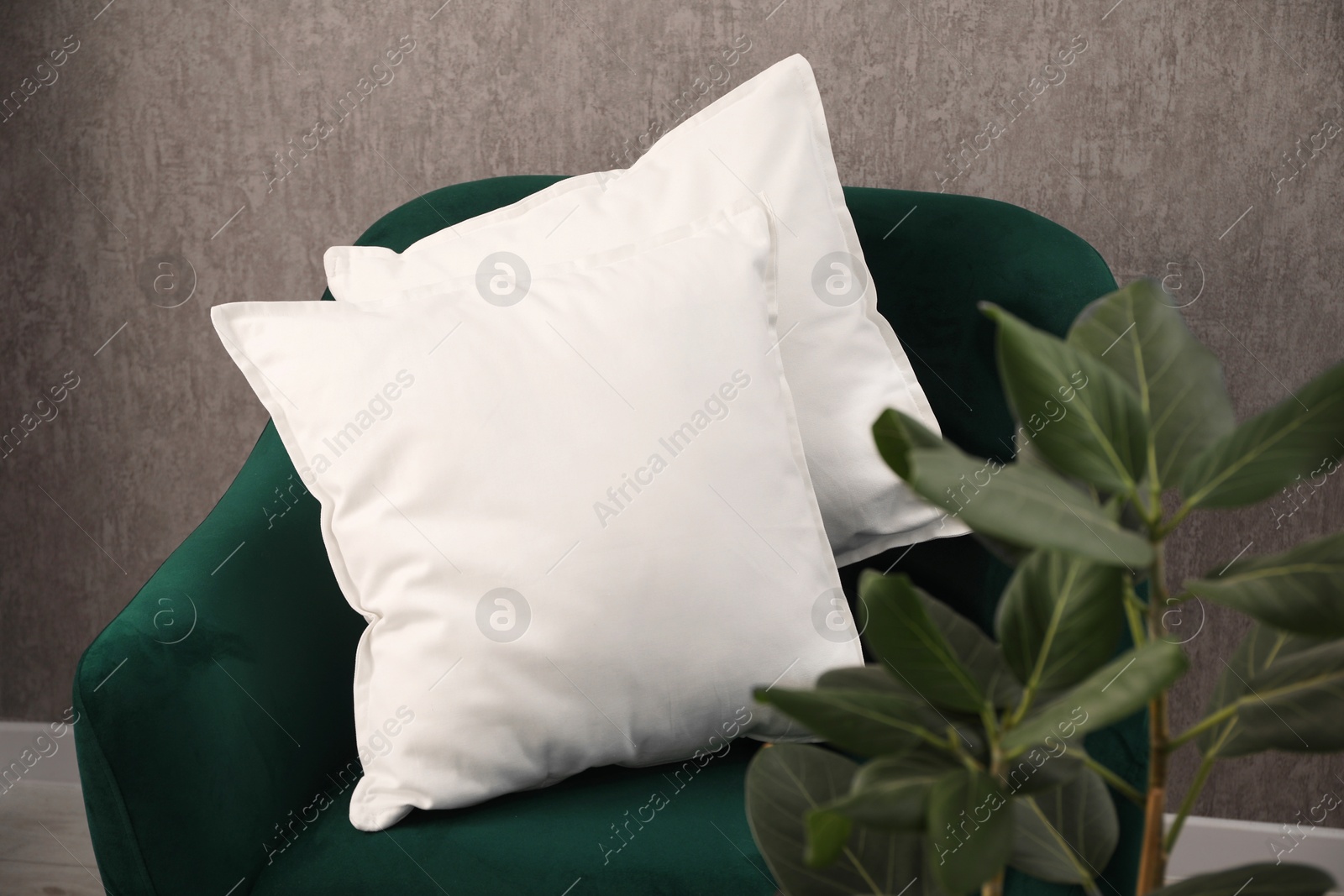 Photo of Soft pillows on green armchair in room