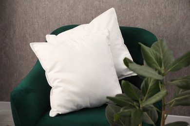 Photo of Soft pillows on green armchair in room