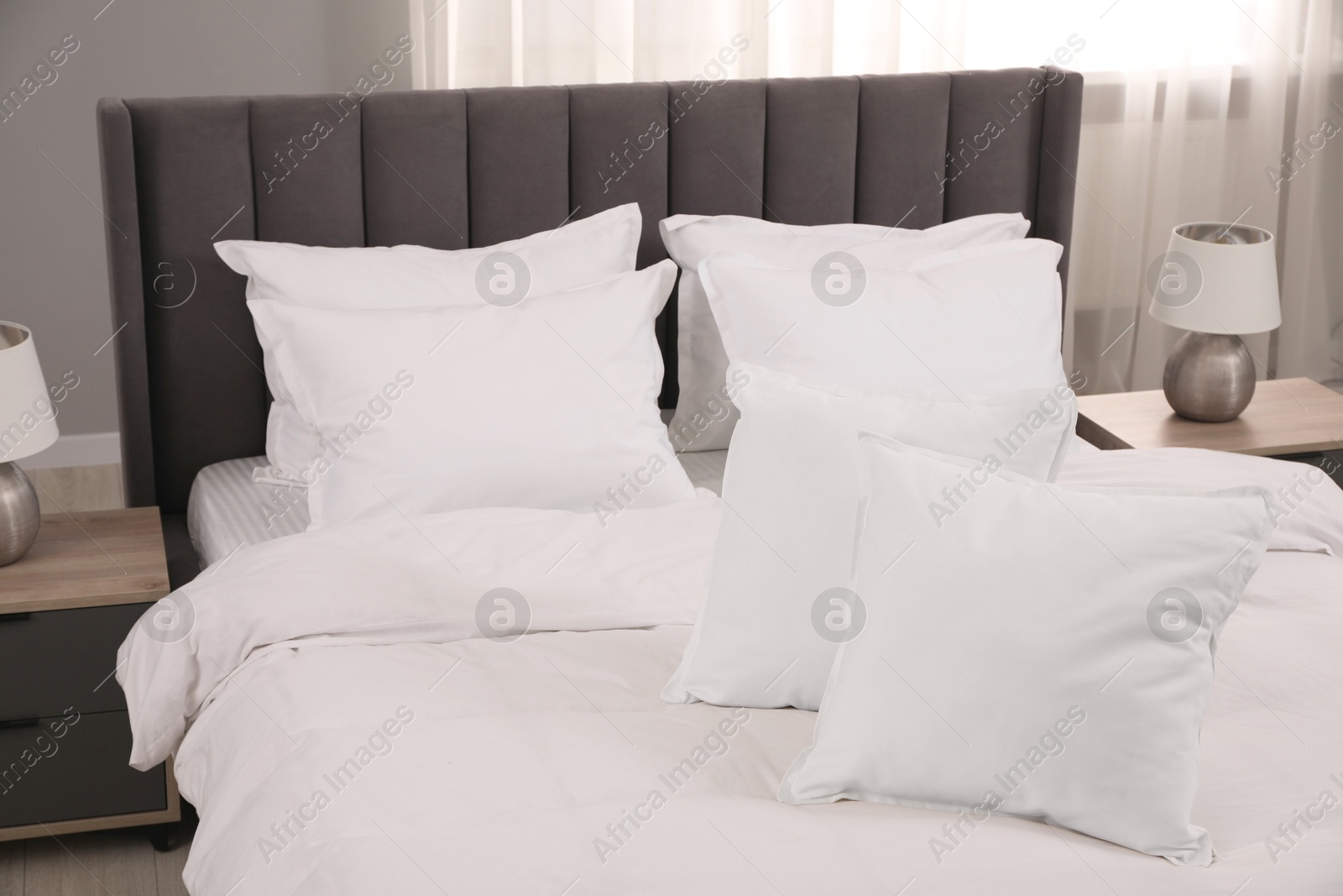 Photo of Many soft white pillows and duvet on bed indoors