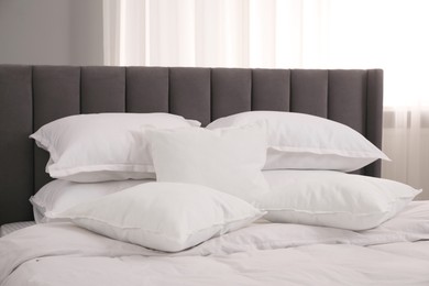 Many soft white pillows and duvet on bed indoors