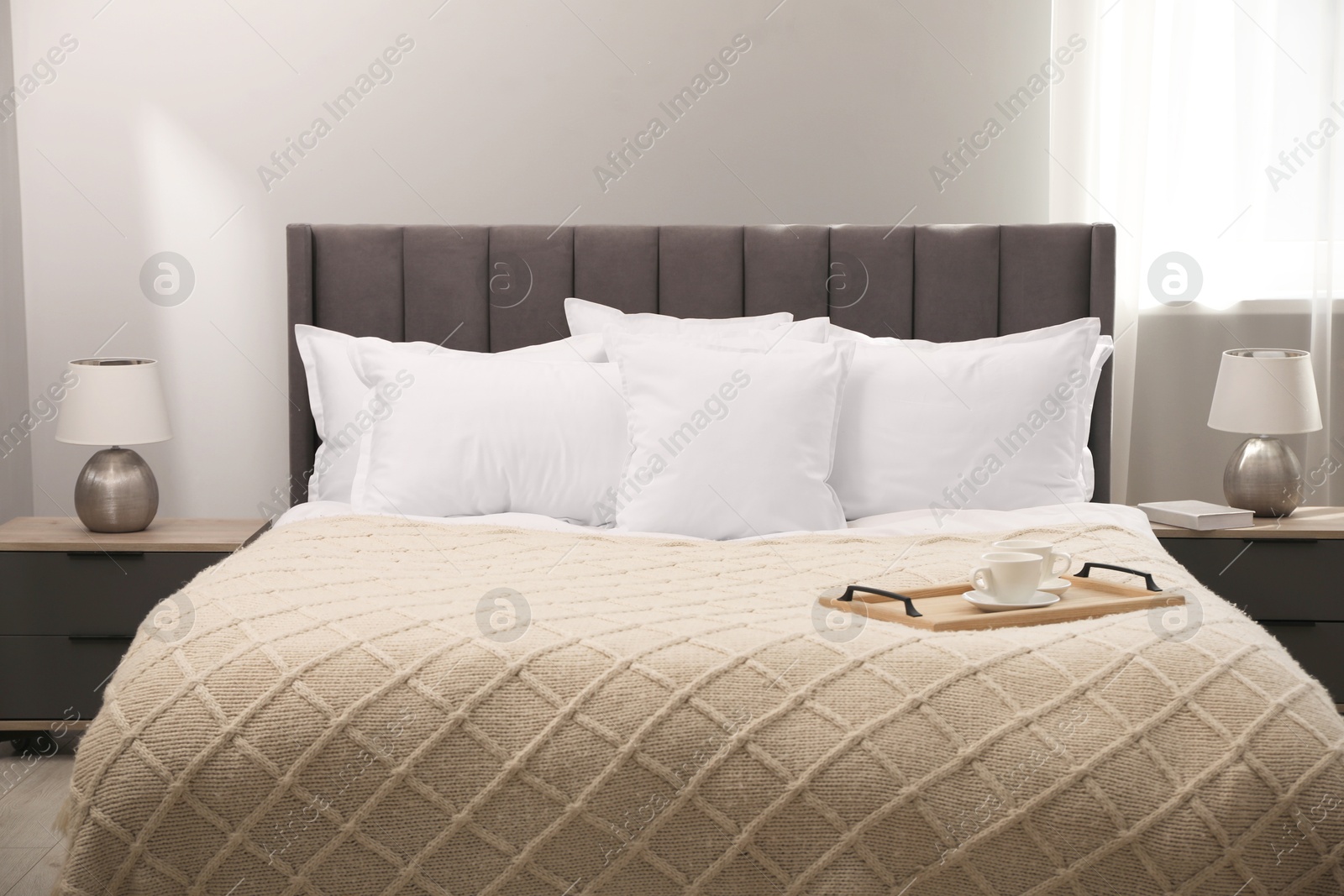 Photo of Many soft white pillows and knitted blanket on bed indoors