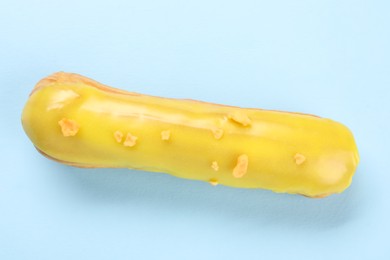 Delicious eclair covered with glaze on light blue background, top view