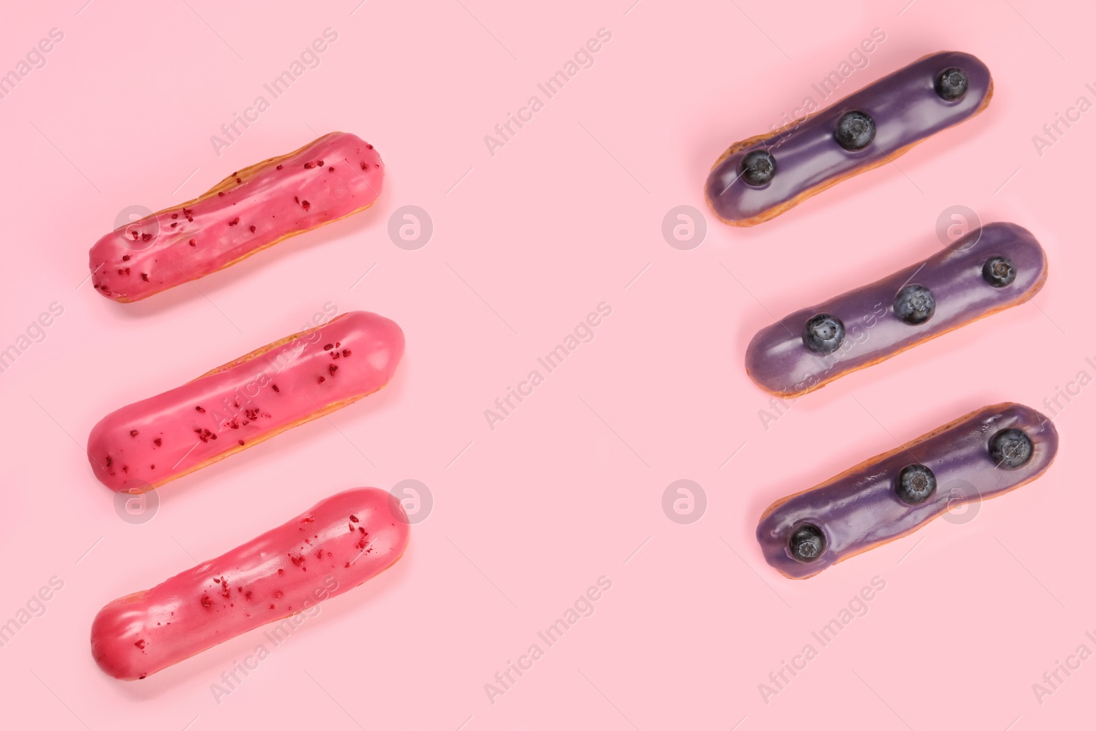 Photo of Delicious eclairs covered with glaze on pink background, top view. Space for text