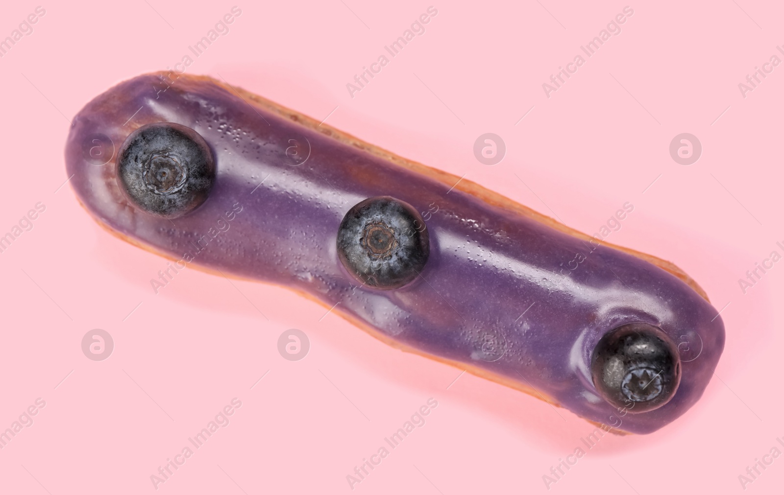 Photo of Delicious eclair decorated with blueberries on pink background, top view