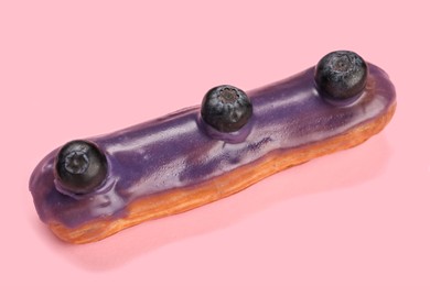 Photo of Delicious eclair decorated with blueberries on pink background