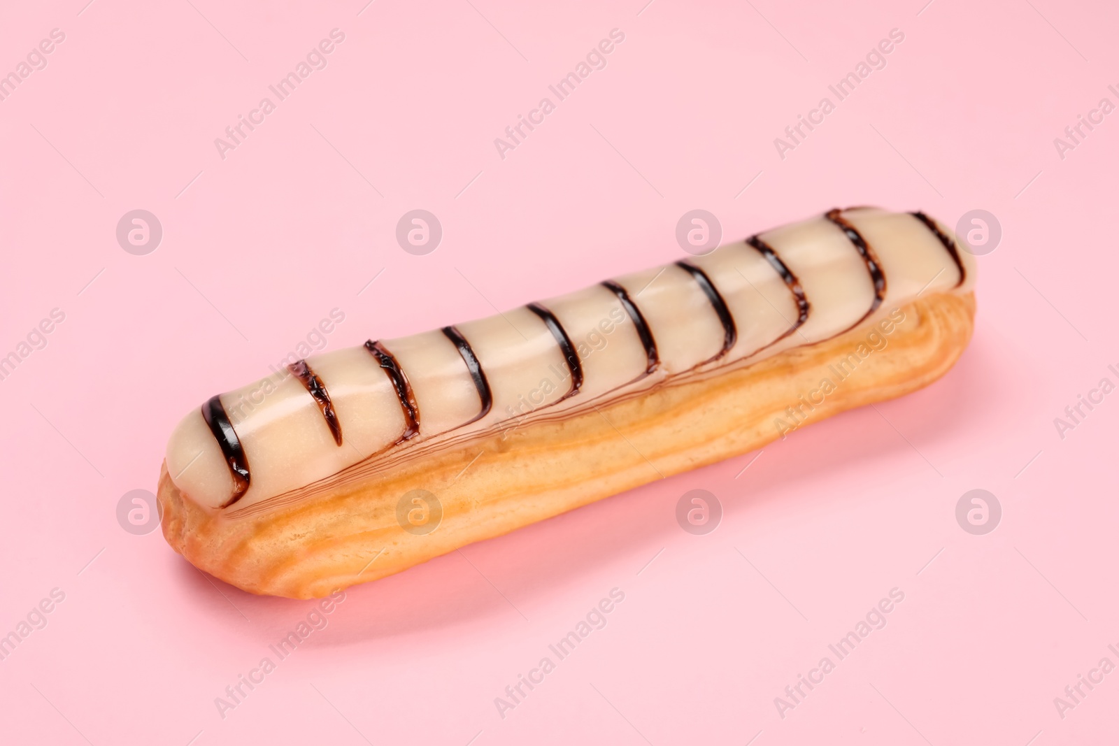 Photo of Delicious eclair covered with glaze on pink background