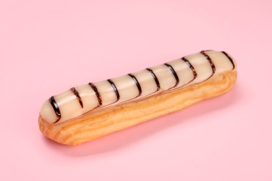 Photo of Delicious eclair covered with glaze on pink background