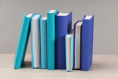 Many colorful books on white wooden table against light grey background