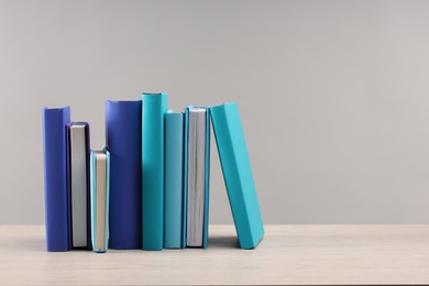 Photo of Many colorful books on white wooden table against light grey background, space for text