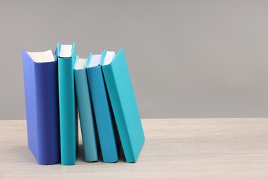 Photo of Many colorful books on white wooden table against light grey background, space for text