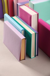 Photo of Many colorful books on beige background, closeup