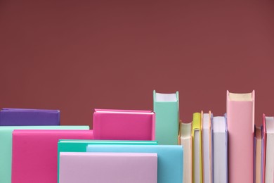 Photo of Many colorful books on pink background, space for text