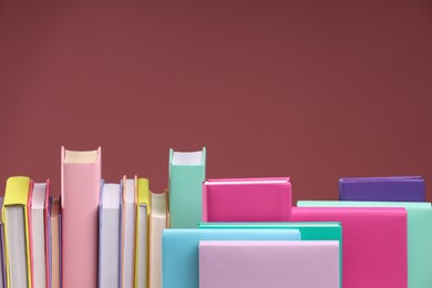 Photo of Many colorful books on pink background, space for text