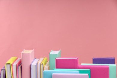 Many colorful books on pink background, space for text