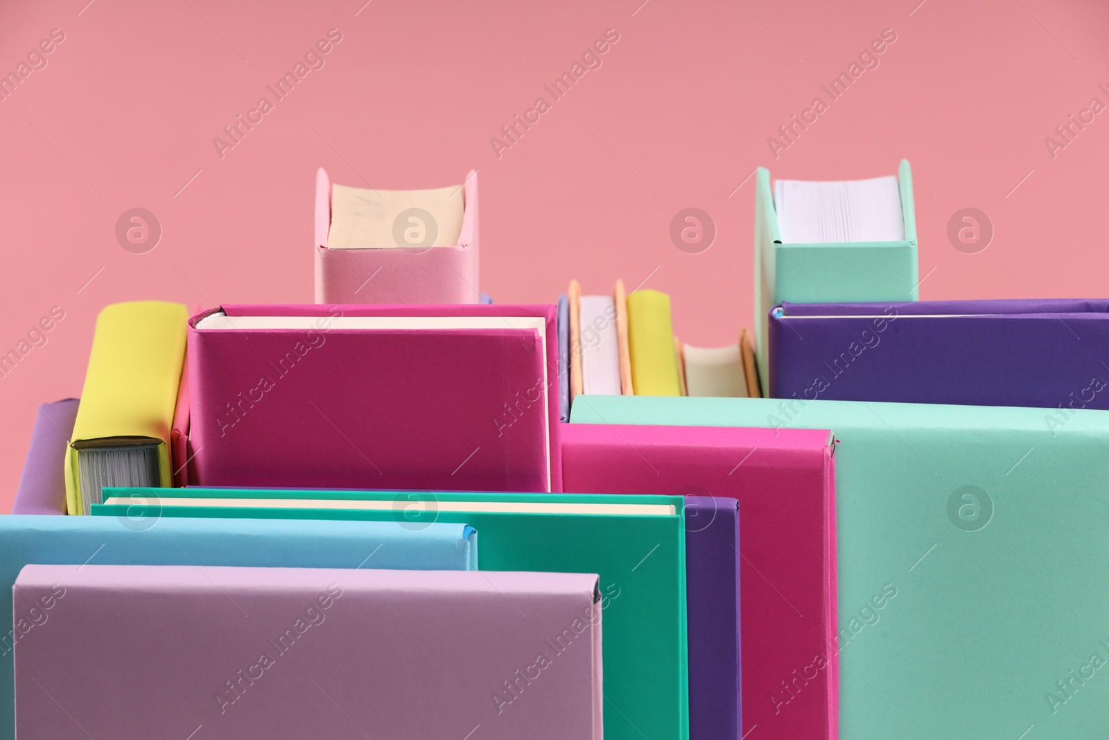 Photo of Many colorful hardcover books on pink background