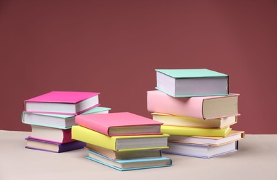 Photo of Many colorful books on beige table against pink background