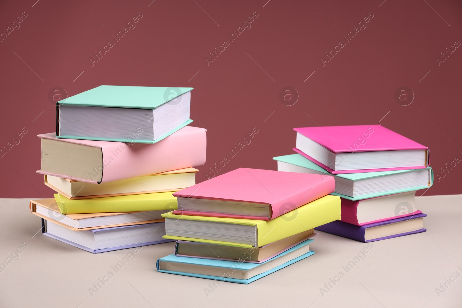 Photo of Many colorful books on beige table against pink background